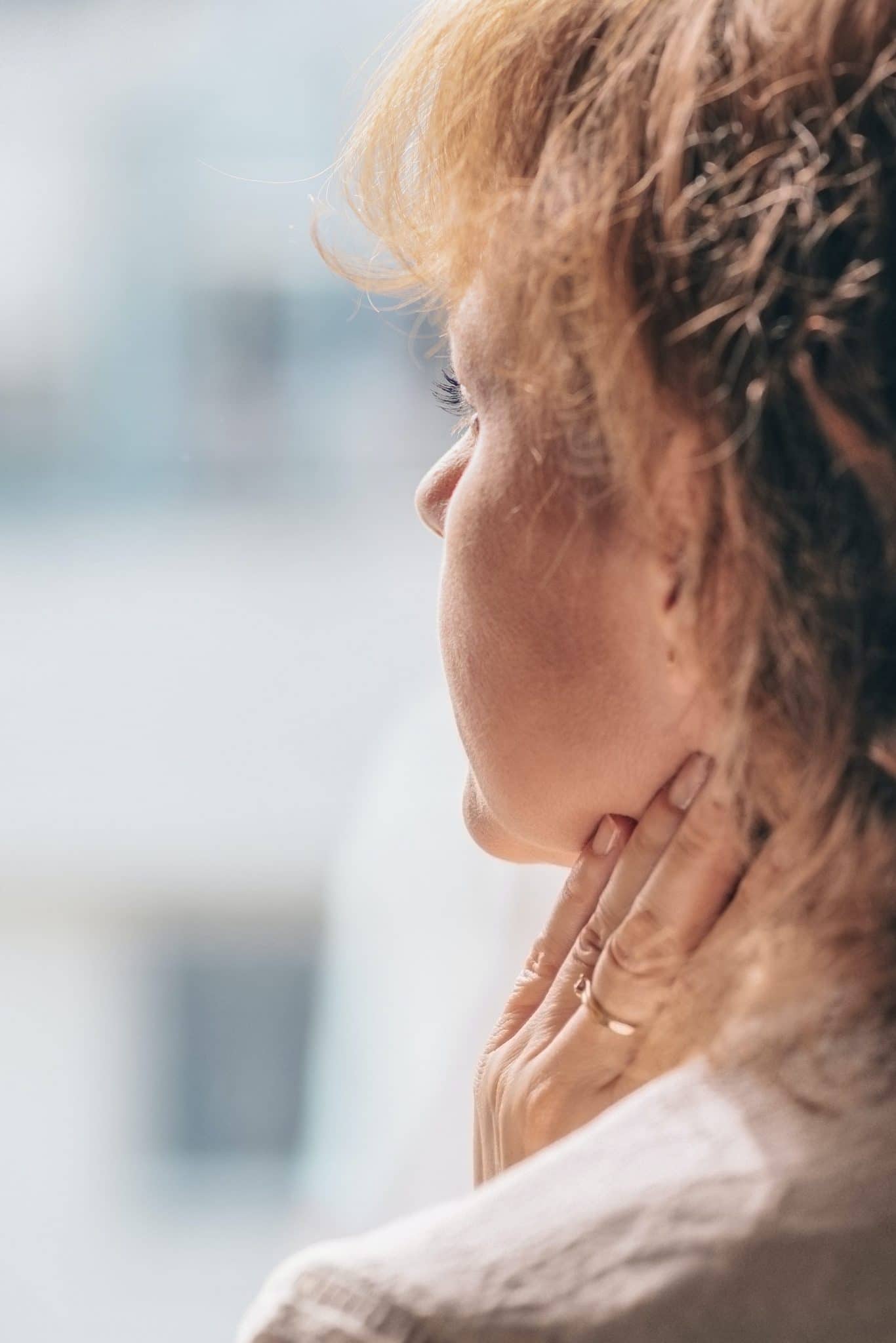 Woman feeling her neck for a lump.