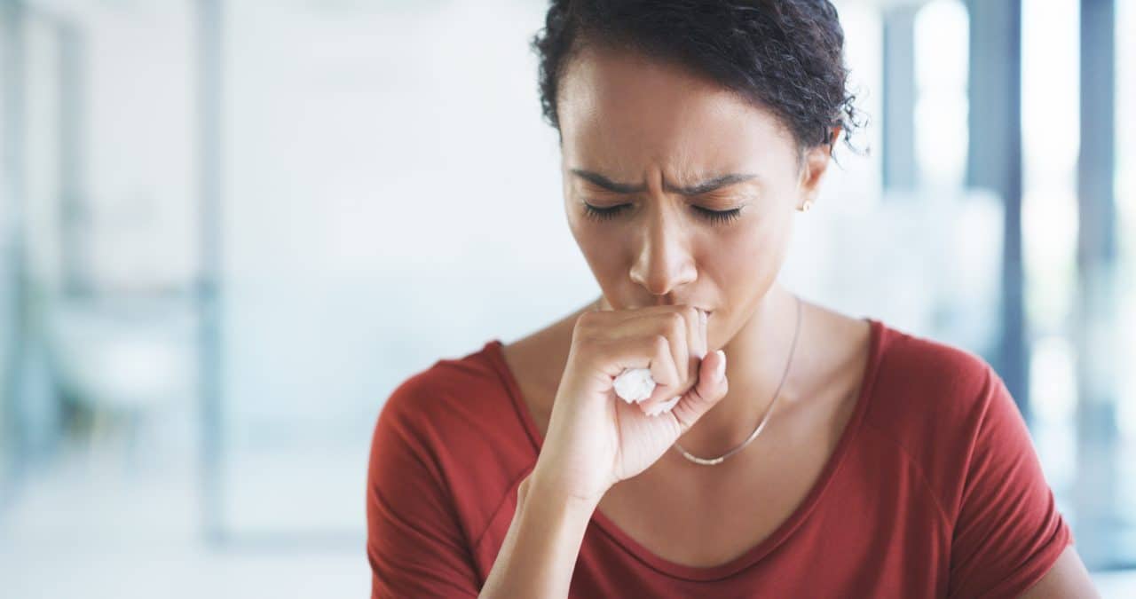Adult woman coughing in her office.